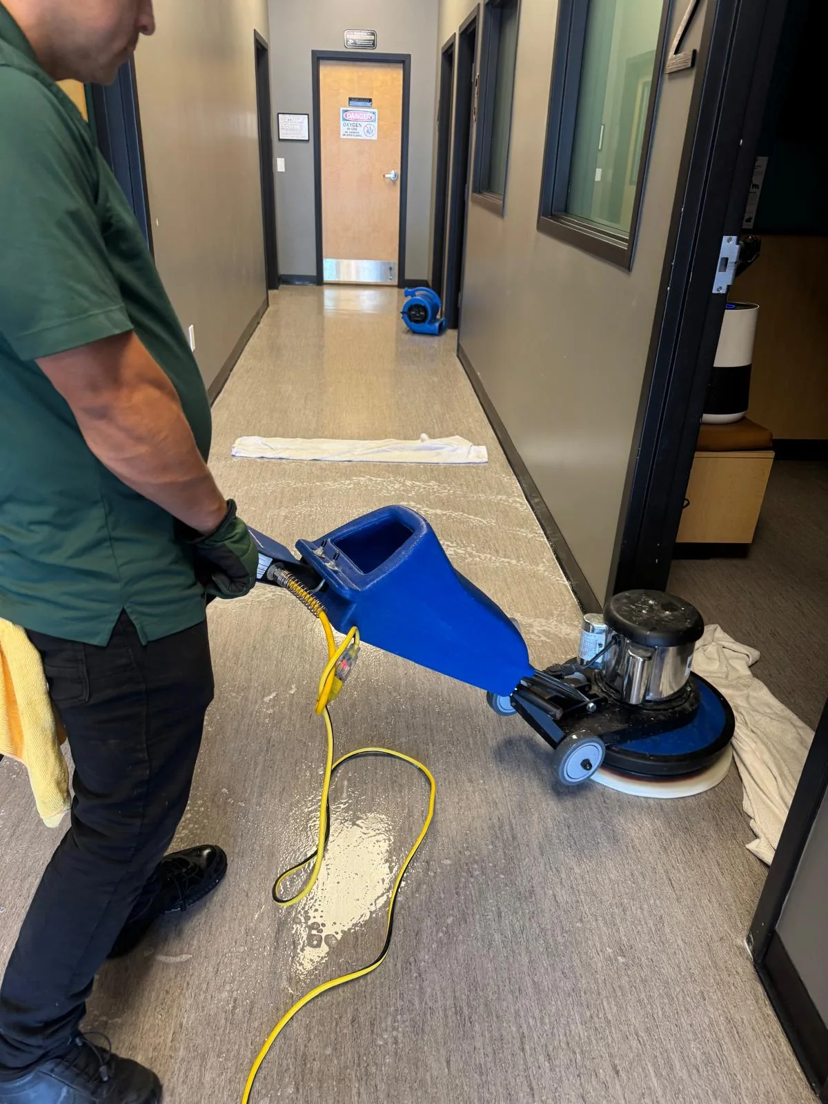 Technician using a rotary machine to clean the floor of a veterinary clinic